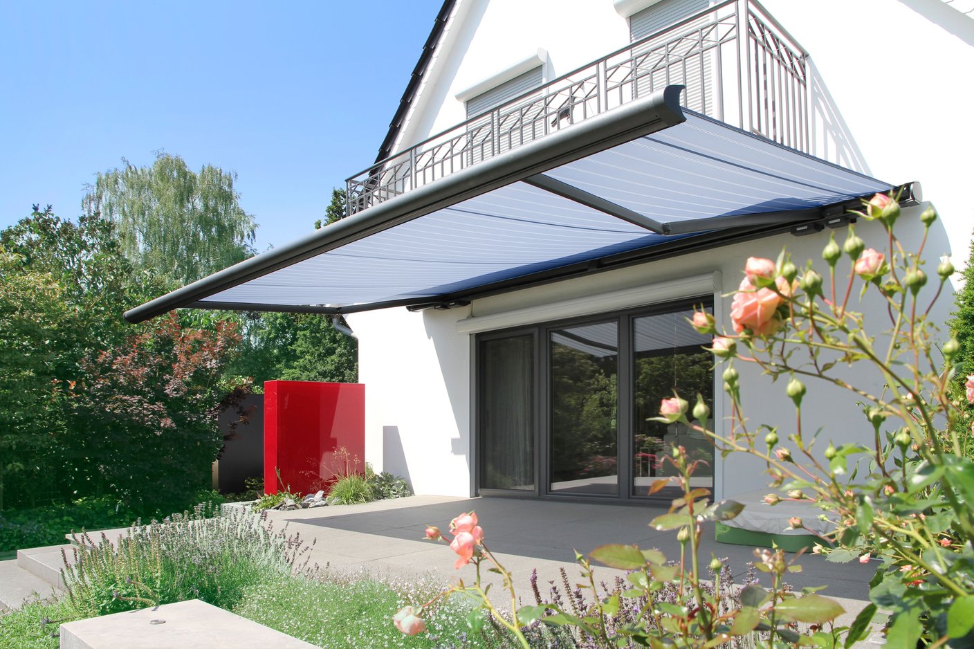 Kassettenmarkise markilux 6000 mit orangenem Tuch und grauem Gestell über einer Terrasse